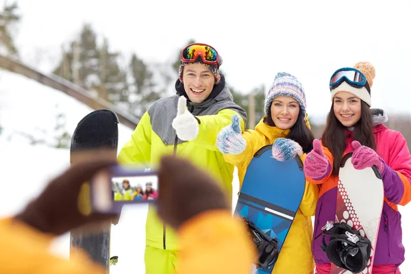 Amigos felices con tablas de snowboard y smartphone —  Fotos de Stock