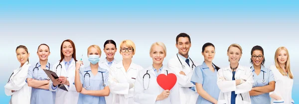 Leende läkare och sjuksköterskor med rött hjärta — Stockfoto