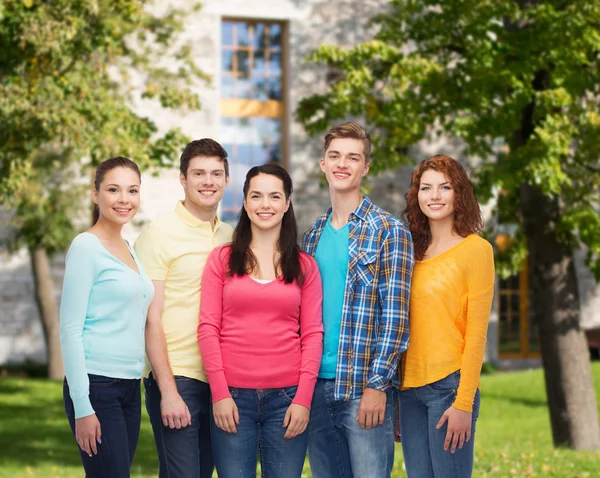 Group of smiling teenagers over campus background — Stock Photo, Image