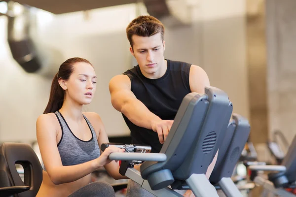Woman with trainer on exercise bike in gym — Stock Photo, Image