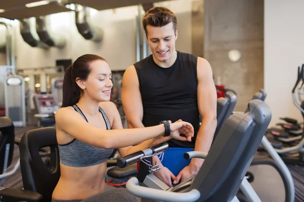 Femme heureuse avec entraîneur sur vélo d'exercice dans la salle de gym — Photo