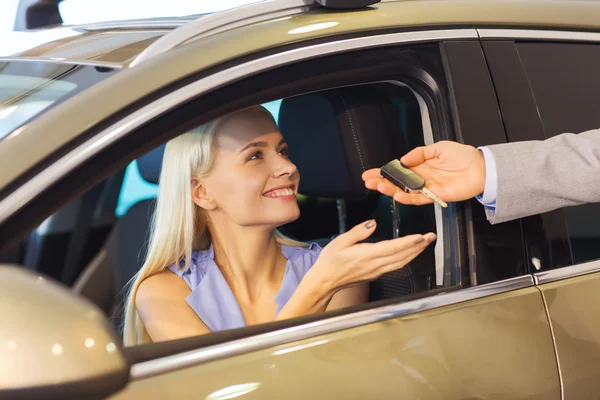 Mulher feliz recebendo chave do carro em auto show ou salão — Fotografia de Stock