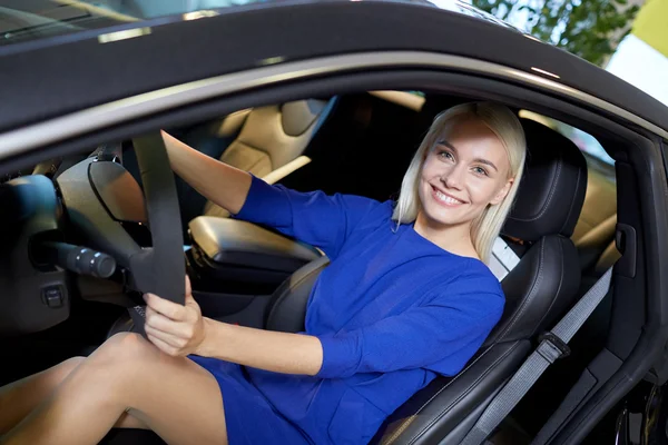 Gelukkig vrouw in auto in auto show of salon — Stockfoto