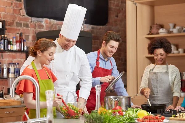 Amici felici e cuoco cucinare in cucina — Foto Stock