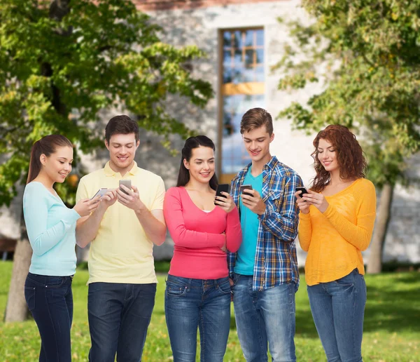 Группа улыбающихся подростков со смартфонами — стоковое фото
