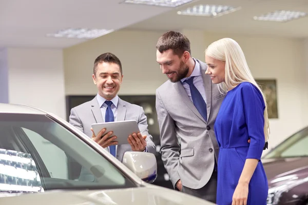 Casal feliz com revendedor de carro em auto show ou salão Imagem De Stock