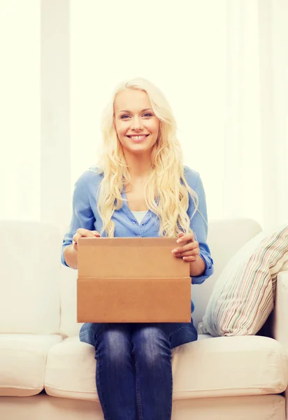 Sonriente joven mujer abriendo caja de cartón — Foto de Stock