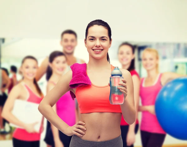 Sportovní žena s ručníkem a láhev s vodou — Stock fotografie