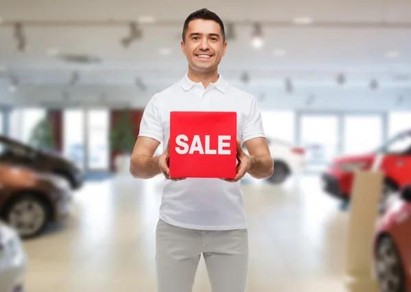 Счастливый человек со вздохом продажи на фоне автосалона — стоковое фото