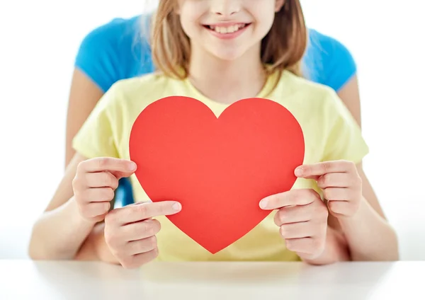 Close up of girl and mother holding red heart — Stock Photo, Image