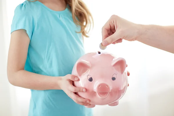Close up de menina com porquinho banco colocando moeda — Fotografia de Stock