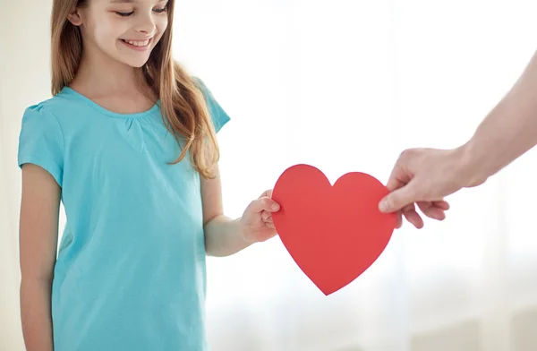 Primer plano de la niña y la mano masculina sosteniendo el corazón rojo — Foto de Stock