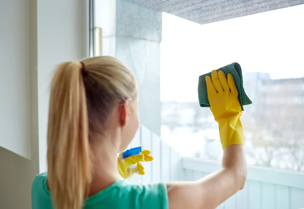 Happy woman in gloves cleaning window with rag — Stock Photo, Image