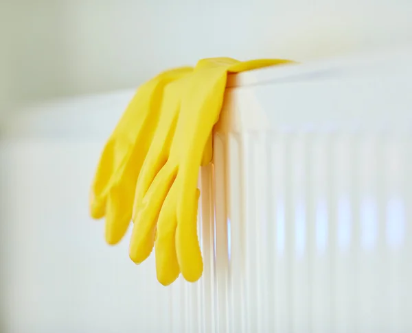 Close up of rubber gloves hanging on heater — Stock Photo, Image