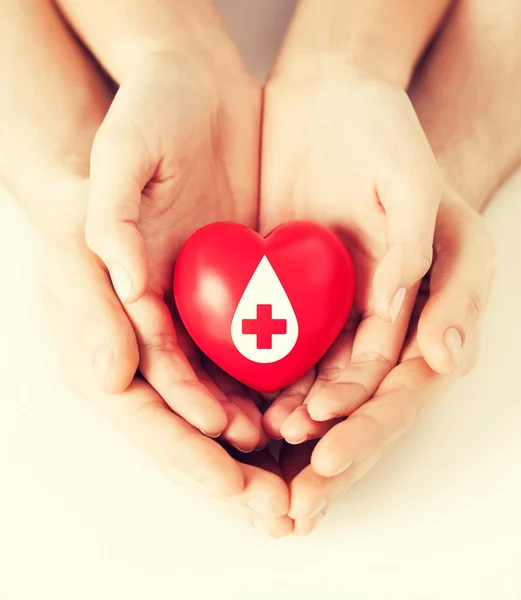 Manos sosteniendo el corazón rojo con signo de donante — Foto de Stock