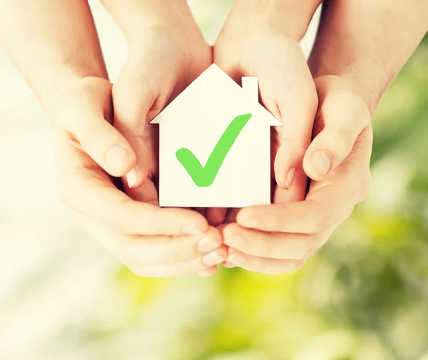 Mãos segurando casa com marca de verificação — Fotografia de Stock