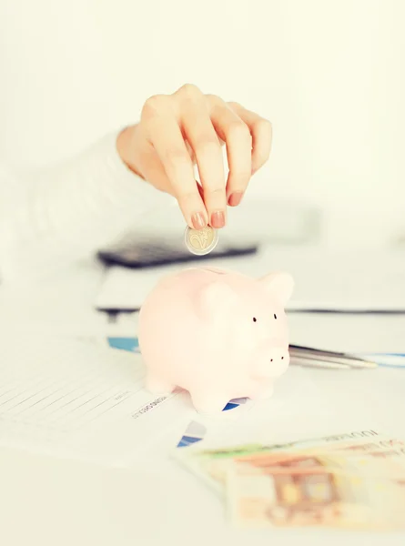 Woman puts euro in piggy bank — Stock Photo, Image