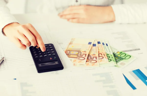 Mãos com calculadora e dinheiro do euro — Fotografia de Stock