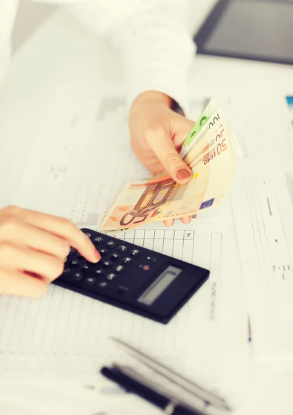 Mãos com calculadora e dinheiro do euro — Fotografia de Stock