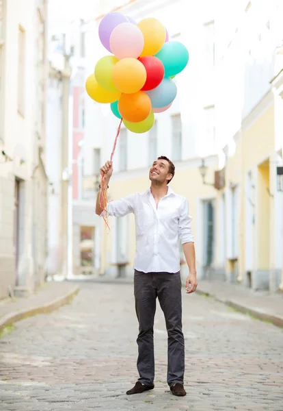 Man med färgglada ballonger i city — Stockfoto