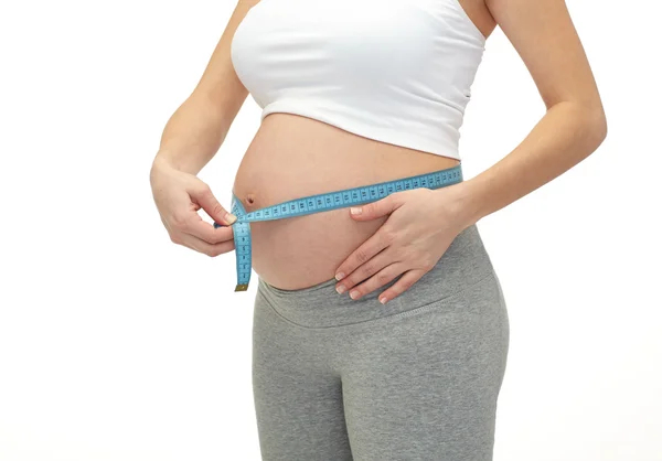 Gravid kvinna mäta hennes mage — Stockfoto
