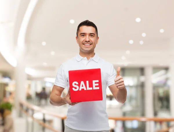 Hombre sonriente con letrero rojo de venta —  Fotos de Stock