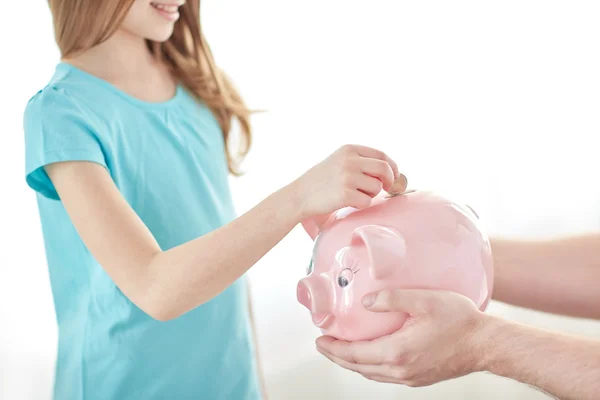 Menina colocando moeda no banco porquinho — Fotografia de Stock