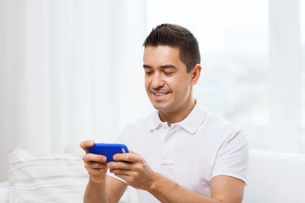 Счастливый человек со смартфоном дома — стоковое фото
