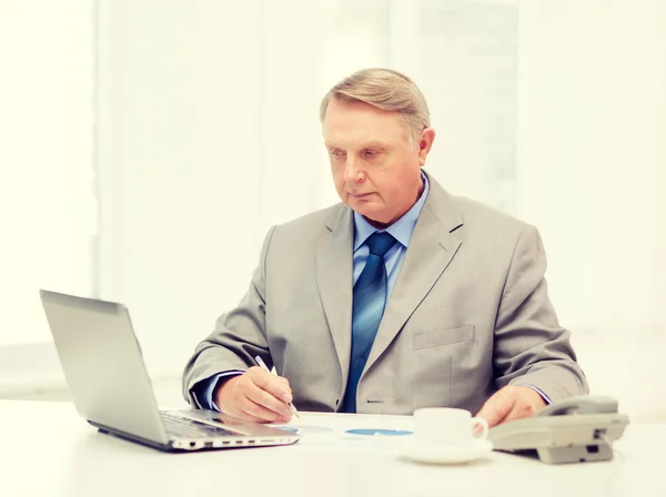 Older businessman with laptop and telephone — Stock Photo, Image