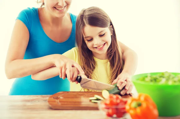 Menina com mãe cortando pepino — Fotografia de Stock