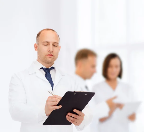 Serious male doctor with clipboard — Stock Photo, Image