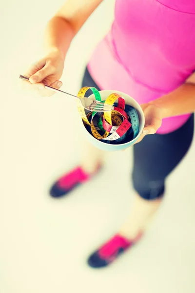 Woman   holding bowl with measuring tape — Stock Photo, Image