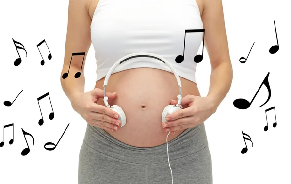 Mujer embarazada y auriculares en la barriga — Foto de Stock