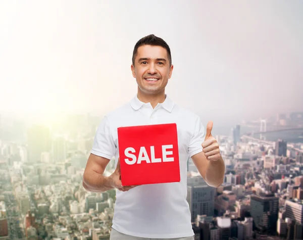 Hombre sonriente con letrero rojo de venta —  Fotos de Stock