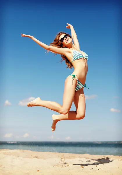 Frau im Bikini springt am Strand — Stockfoto