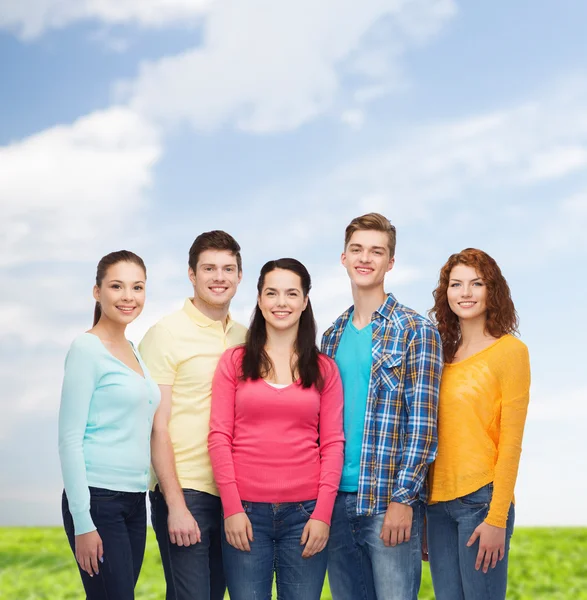 Groep van lachende tieners over blauwe hemel en gras — Stockfoto