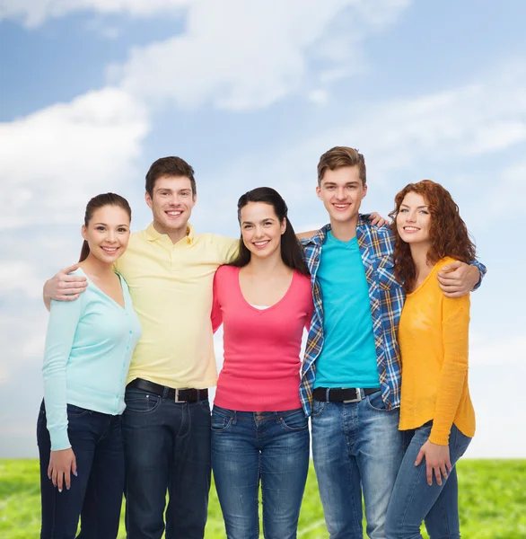 Groep van lachende tieners over blauwe hemel en gras — Stockfoto