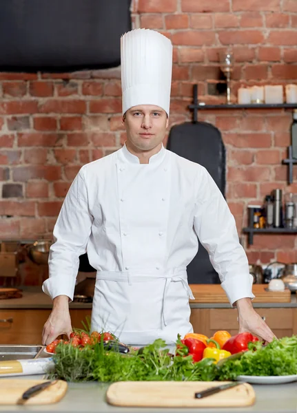 Gelukkig mannelijke chef-kok koken met groenten in de keuken — Stockfoto