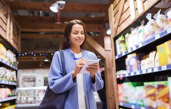 Mujer feliz con bloc de notas en el mercado — Foto de Stock