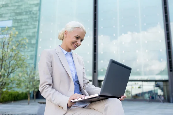 Sonriente mujer de negocios trabajando con el ordenador portátil al aire libre —  Fotos de Stock