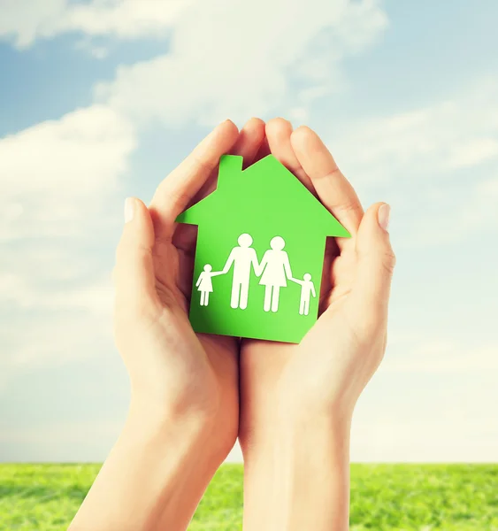 Hands holding green house with family — Stock Photo, Image