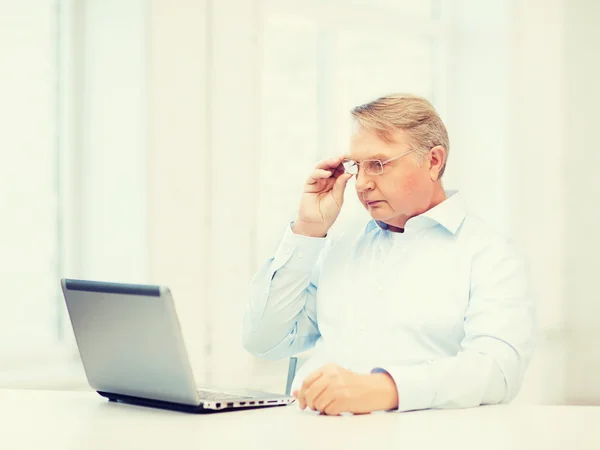 Oude man in brillen werken met laptop thuis — Stockfoto