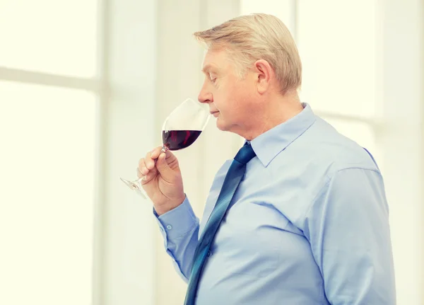 Hombre mayor oliendo vino tinto — Foto de Stock
