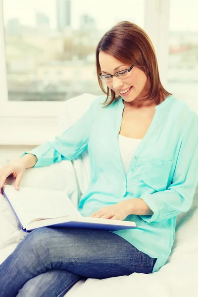 Lächelnde Frau liest Buch und sitzt auf Couch — Stockfoto