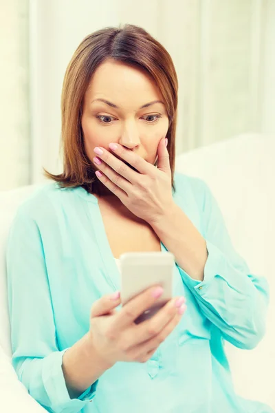 Frau zu Hause mit Smartphone überrascht — Stockfoto