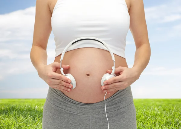 Zamknij się kobiety w ciąży i słuchawki na brzuch — Zdjęcie stockowe