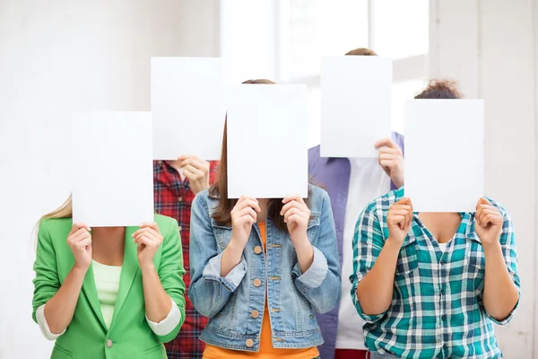 Studenten die betrekking hebben op gezichten met lege papieren — Stockfoto