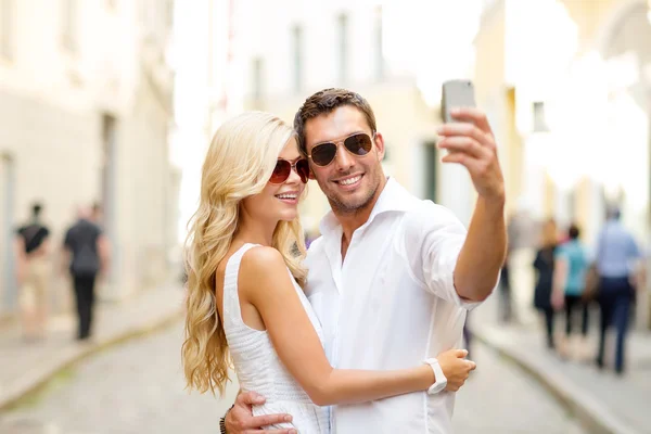 Улыбающаяся пара со смартфоном в городе — стоковое фото