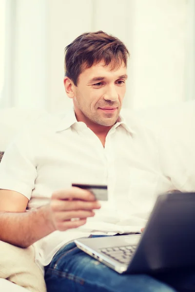 Man met laptop en een creditcard bij u thuis — Stockfoto