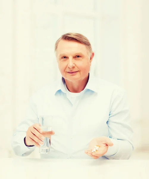 Viejo con pastillas y un vaso de agua — Foto de Stock